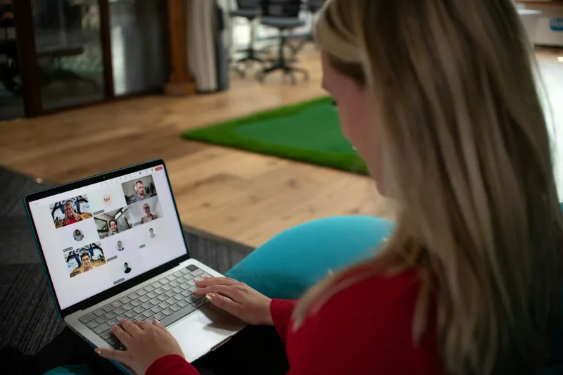 Spreker sluit vanaf een andere locatie aan via haar laptop, met de online deelnemers in beeld.